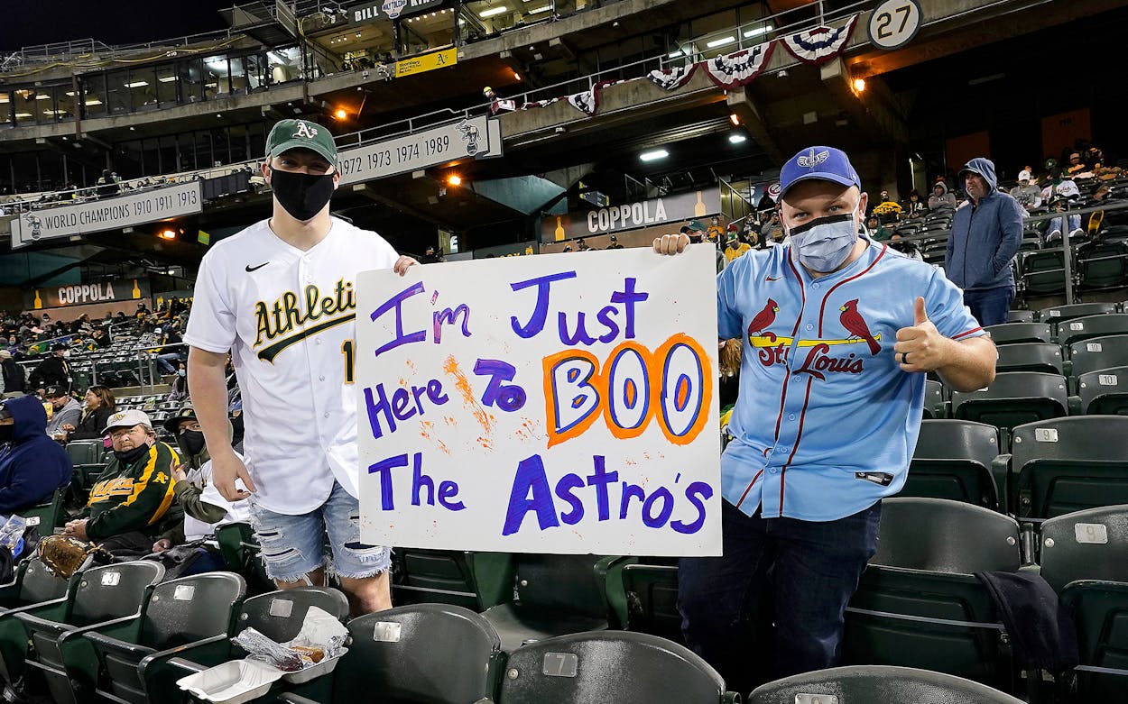 Fans pose with a sign against the Houston Astros during the game with the Oakland Athletics at RingCentral Coliseum on April 02, 2021 in Oakland, California.